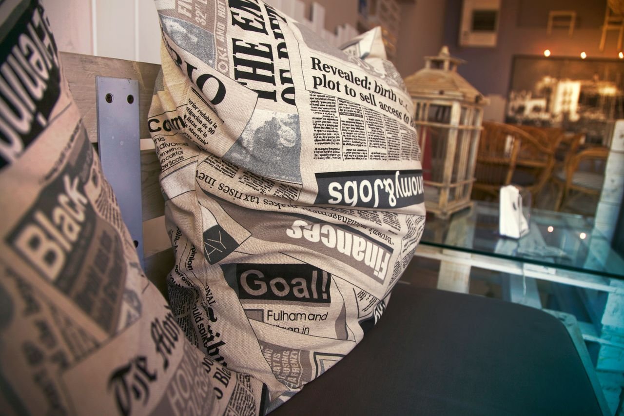 Stylish cafe setting featuring pillows with newspaper print, creating a comfy atmosphere.