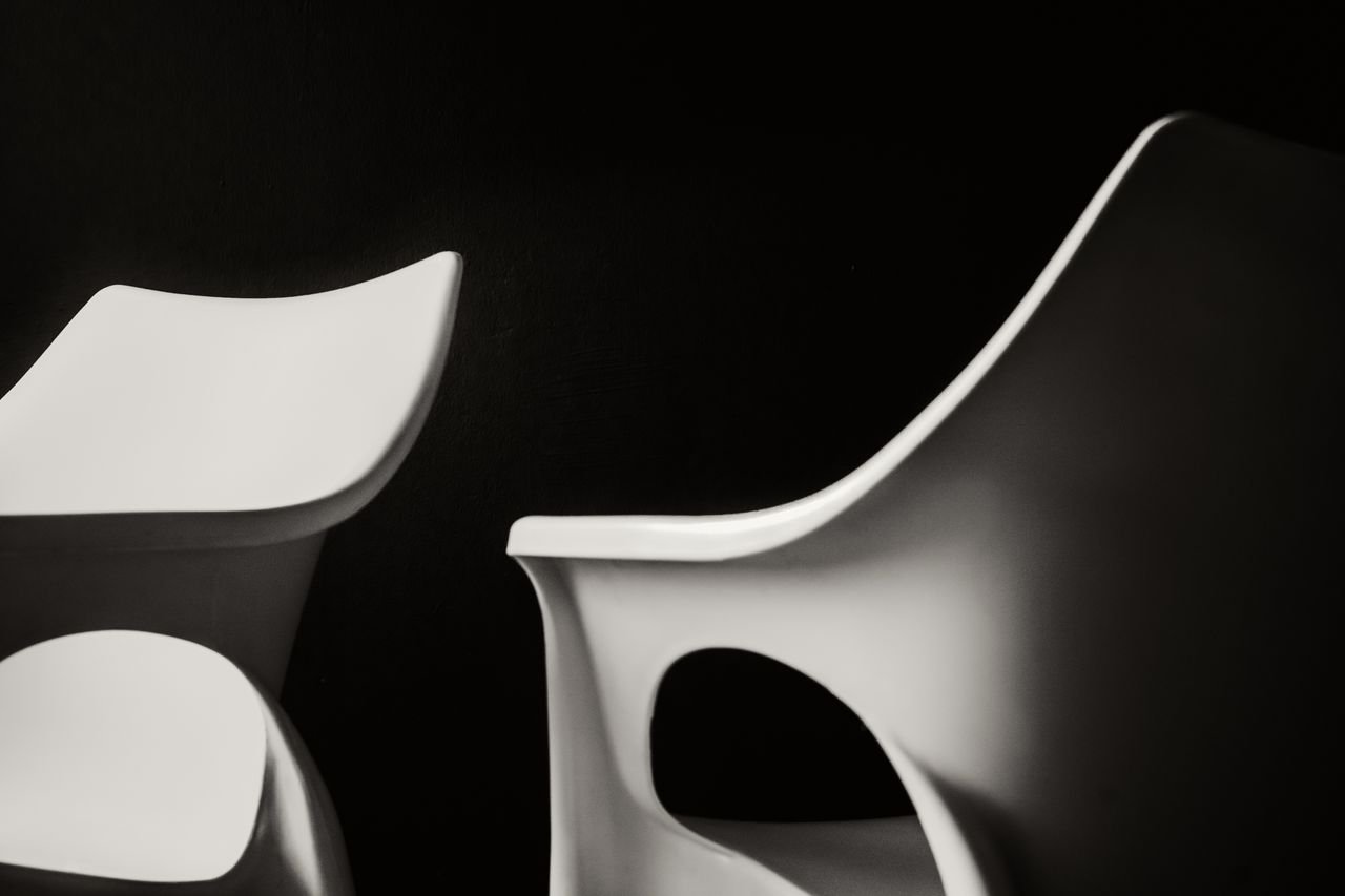 Artistic black and white photo of modern white plastic chairs with a minimalist design.