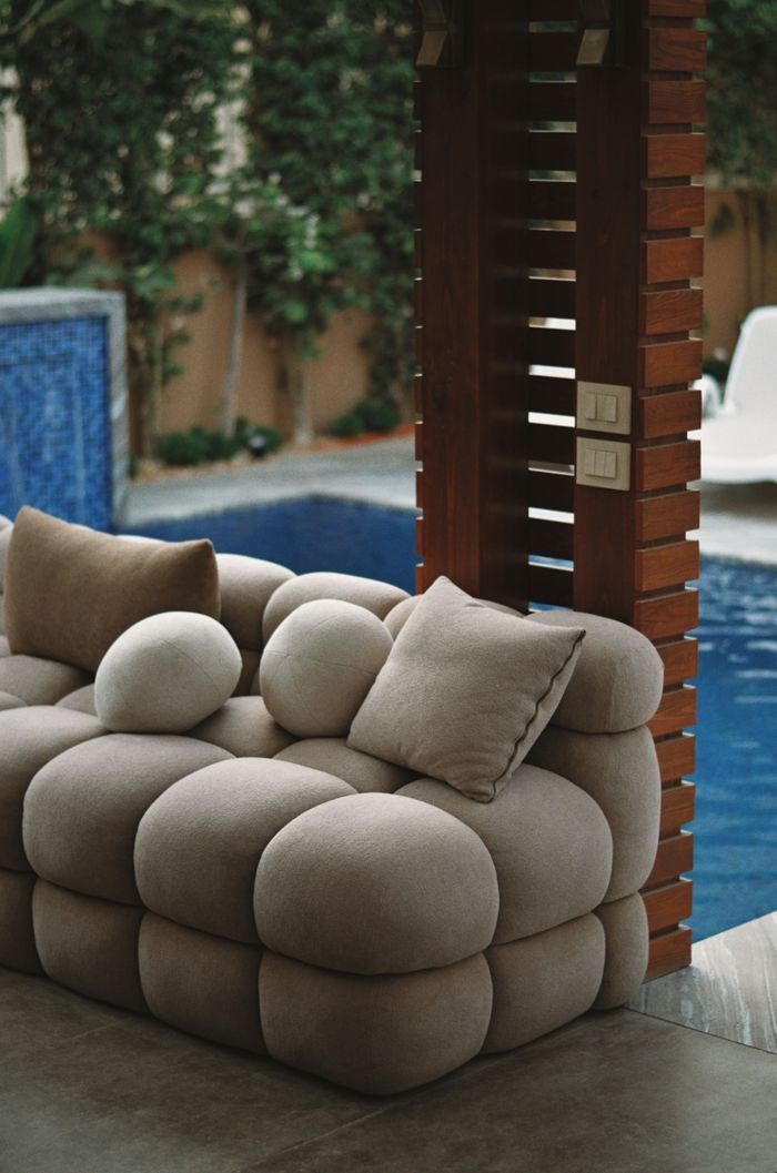 Elegant plush sofa by a pool, offering a cozy outdoor retreat.