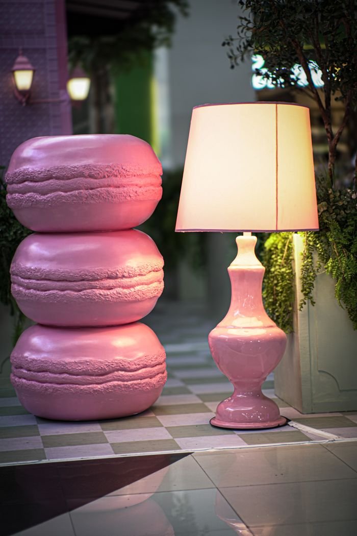 Three large pink macaron sculptures paired with a matching lamp in an indoor setting.