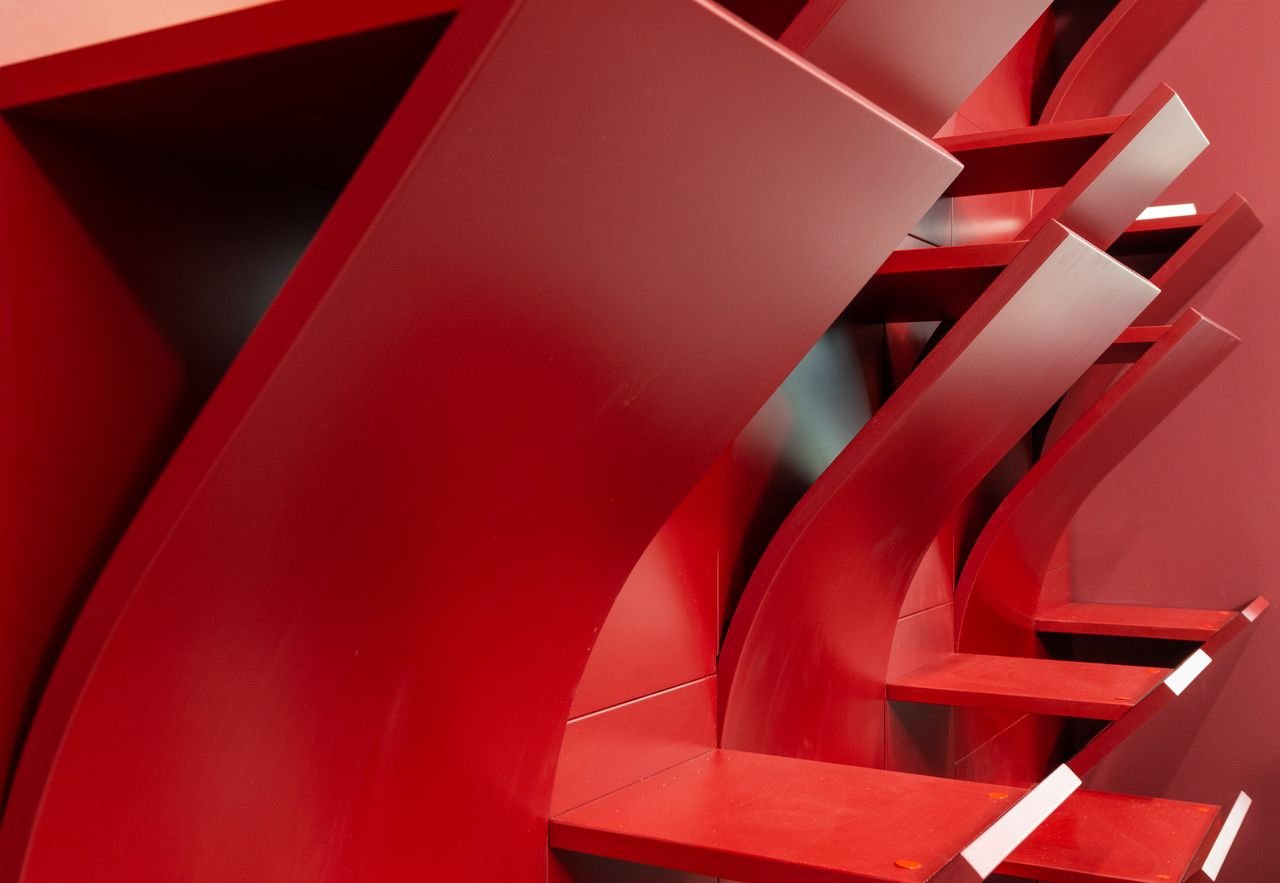 Interior of modern light office with empty red shelves with geometric design near wall